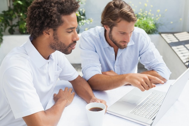 Due amici che godono del caffè insieme al computer portatile