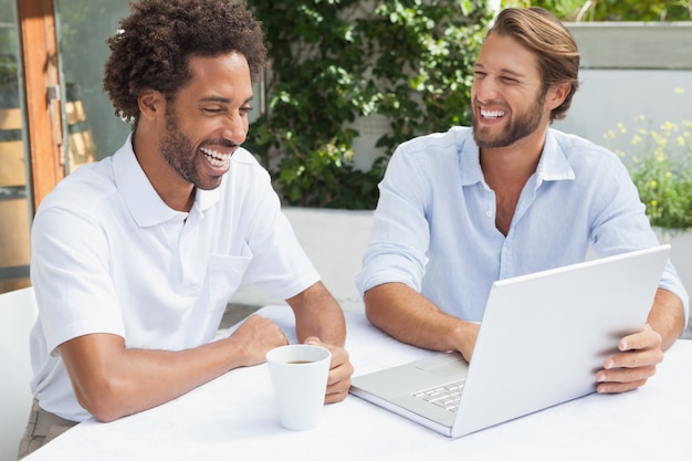 Due amici che godono del caffè insieme al computer portatile