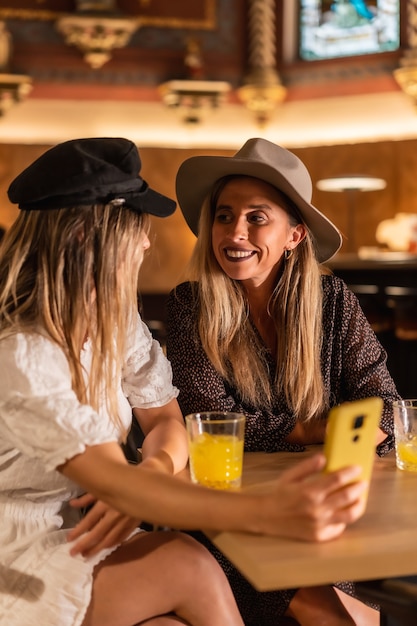 Due amici che guardano un sito web mobile in un ristorante moderno. Sorseggiando una spremuta d'arancia, lifestyle