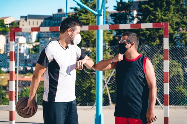 Due amici con la mascherina si salutano prima di iniziare a giocare a basket