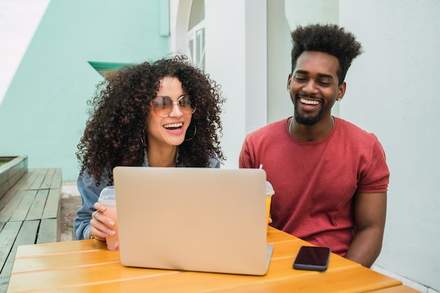 Due amici di afro che per mezzo del computer portatile ad un self-service.