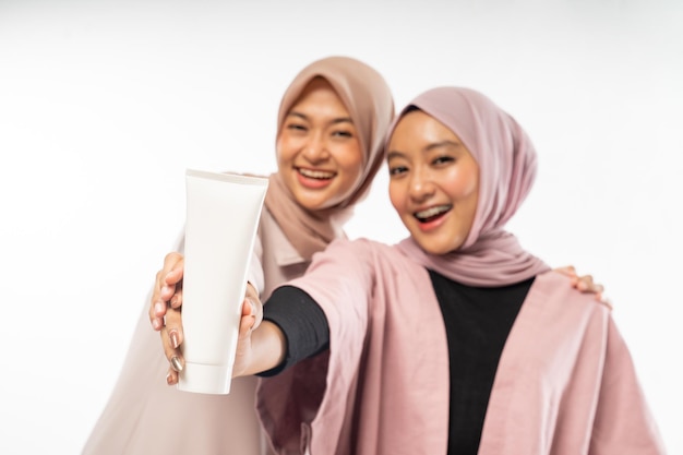 Due amici di bellezza musulmani che tengono un prodotto cosmetico in tubo per la cura della pelle