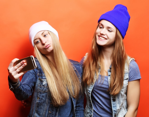 Due amici di ragazze adolescenti in attrezzatura hipster fanno selfie su un pho