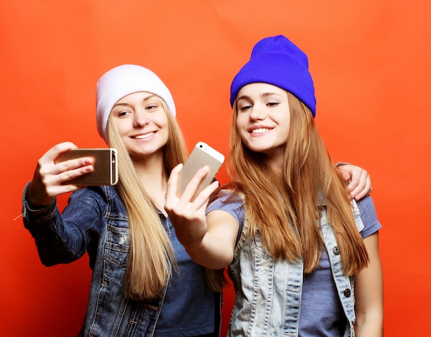 Due amici di ragazze adolescenti in attrezzatura hipster fanno selfie