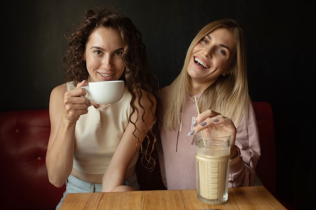 Due amici felici che parlano tenendo una conversazione in una caffetteria