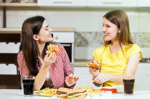 Due amici felici che trascorrono del tempo insieme mangiando gustosi fast food nella cucina di casa con una bella chiacchierata