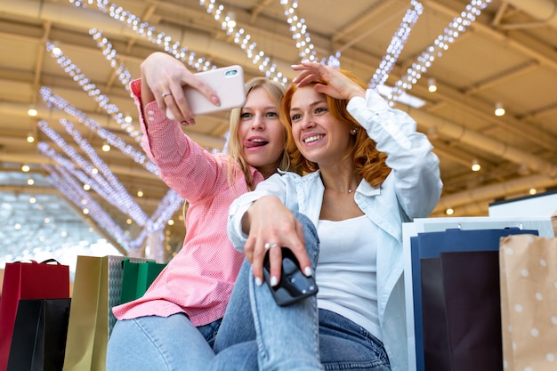 Due amici felici sta prendendo selfie durante lo shopping nel centro commerciale