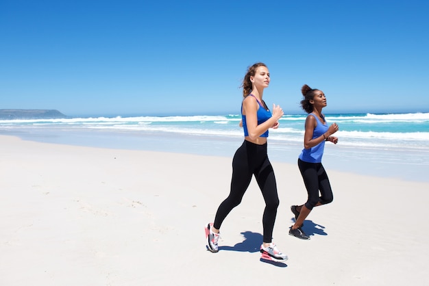 Due amici femminili che corrono sulla spiaggia