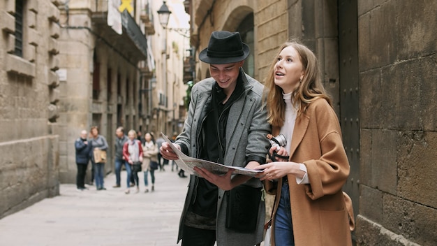 Due amici in piedi in strada e cercano qualcosa usando una mappa.