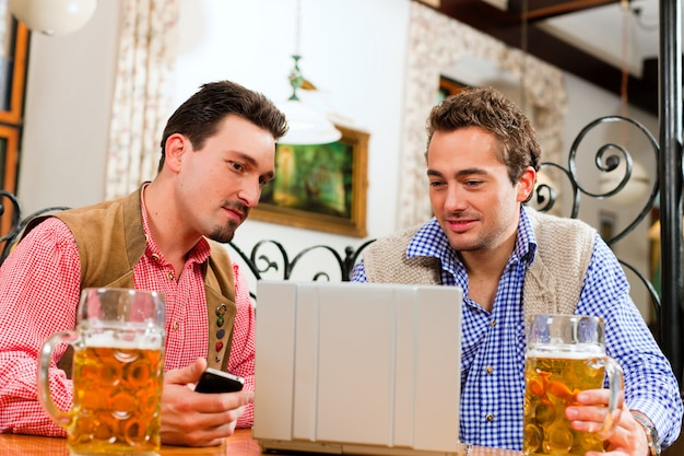 Due amici in un pub bavarese con computer portatile