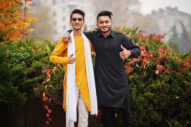 Due amici indiani alla moda in abiti tradizionali posati all'aperto
