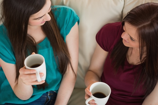 Due amici sorridenti con caffè e chiacchierando sul divano