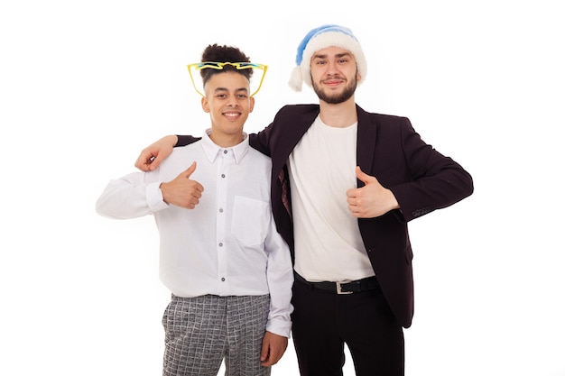 Due amici sorridenti in abbigliamento formale con un cappello blu da Babbo Natale e grandi occhiali da stella che si abbracciano
