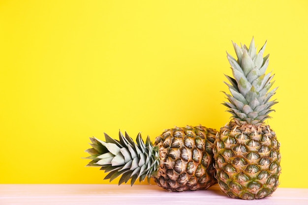 Due ananas maturi su una parete gialla