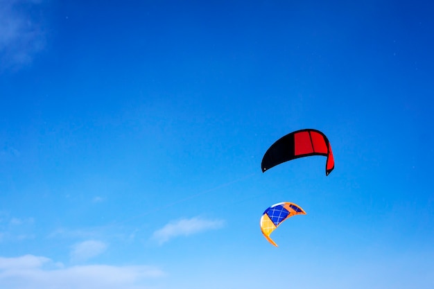 Due aquiloni sportivi multicolori per fare kite o snowkite su uno sfondo di cielo azzurro con nuvole