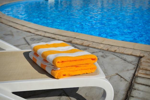 Due asciugamani a strisce gialli si trovano su un lettino vicino a una piscina