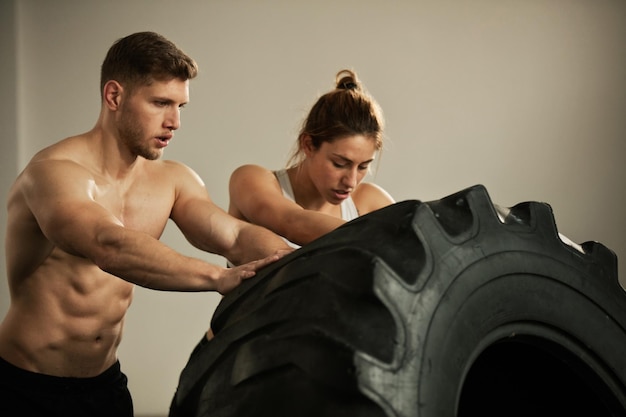 Due atleti che si impegnano nell'allenamento incrociato mentre lanciano insieme pneumatici di grandi dimensioni nel club benessere
