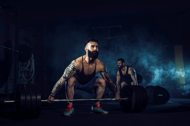 Due atleti tatuati barbuti muscolari che si allenano alla palestra