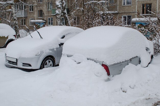 Due auto sotto cumuli di neve dopo la nevicata in inverno non pulite