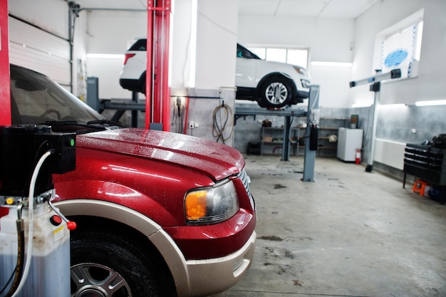 Due auto SUV americane su supporto per il controllo del camber di allineamento delle ruote nell'officina della stazione di servizio