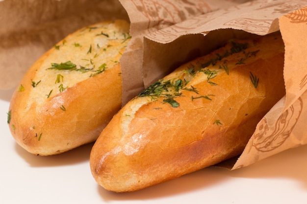 Due baguette ricoperte di erbe aromatiche verdi in sacchetti di carta. primo piano