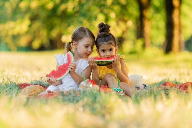 Due bambine carine che mangiano anguria in natura giocano e si divertono concetto di cibo per bambini