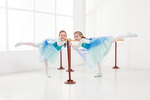 Due bambine carine che usano la sbarra mentre si esercitano in uno studio di danza.