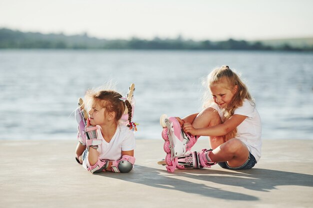 Due bambine con pattini a rotelle all'aperto vicino al lago