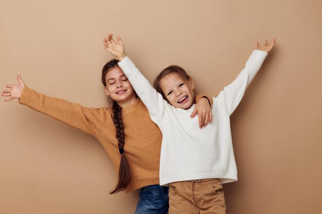 Due bambine divertenti abbracciano l'amicizia in posa su sfondo beige