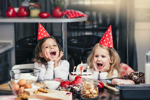 Due bambine felici che festeggiano un compleanno con la torta al tavolo è adorabile e bello