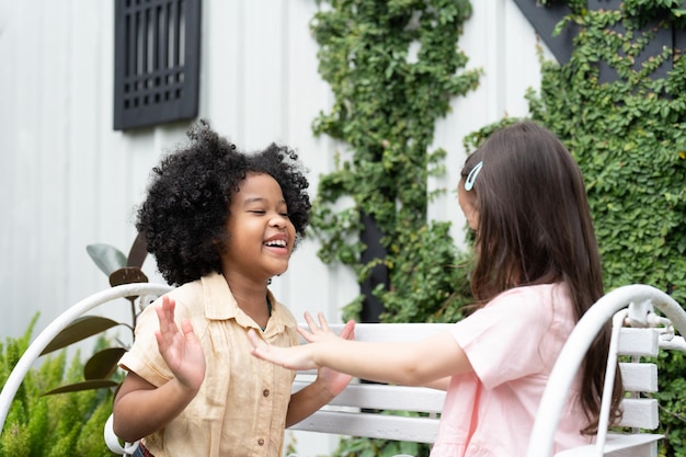 Due bambine felici sedute sulla panchina si divertono a giocare a battere le mani all'aperto a casa