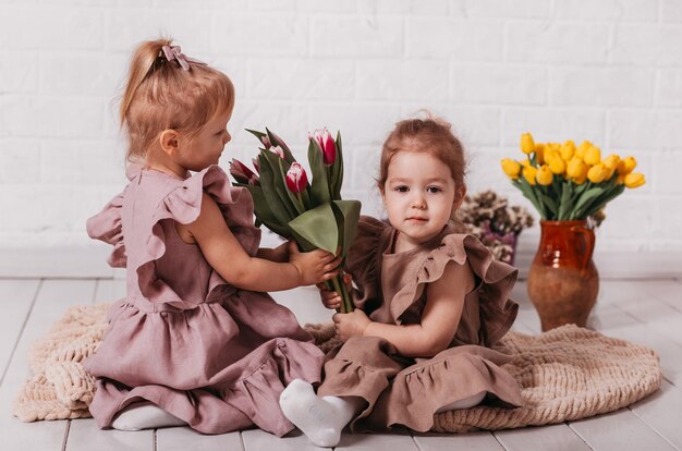 Due bambine in bellissimi abiti in studio con fiori