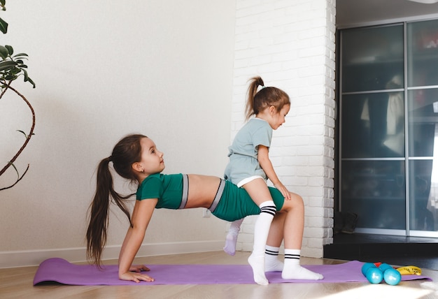 Due bambine in divisa sportiva sono impegnate nel fitness a casa