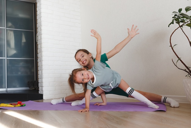 Due bambine in divisa sportiva sono impegnate nel fitness a casa