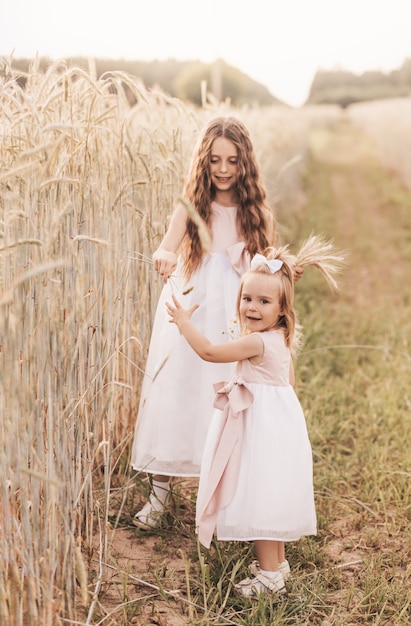 Due bambine raccolgono spighette in un campo di grano