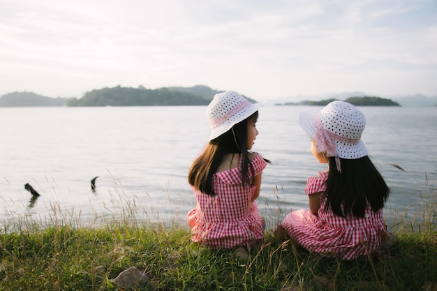 Due bambine sedute sull'erba e guardando l'acqua