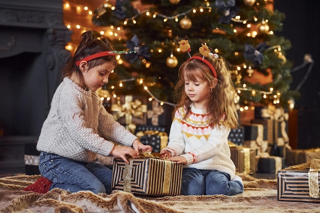 Due bambine si divertono nella stanza decorata di Natale con scatole regalo.