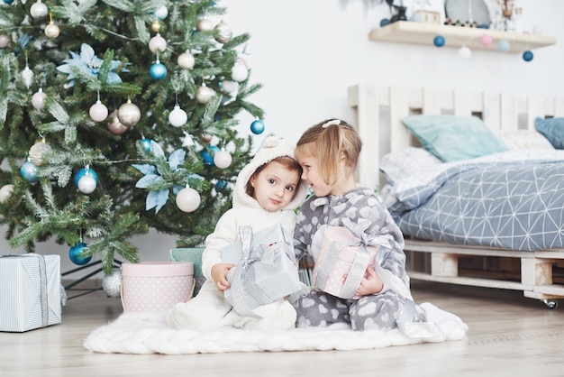 Due bambine sorelle aprono i loro regali all'albero di Natale al mattino sul ponte