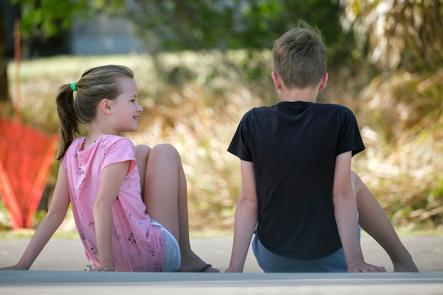 Due bambini adolescenti sorridenti felici un ragazzo e una ragazza seduti all'aperto che riposano divertendosi in una giornata di sole estivo