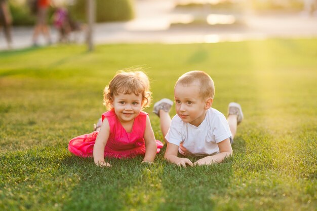 Due bambini allegri che si divertono sdraiati sull'erba verde brillante