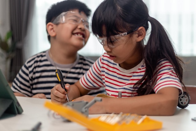 Due bambini asiatici che si divertono a imparare a programmare insieme imparando a distanza a casa STEM scienza homeschooling educazione divertente distanza sociale isolamento nuovo concetto normale