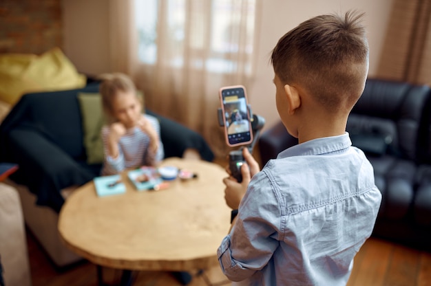 Due bambini blogger registrano blog sulla fotocamera, piccoli vlogger. Blogging per bambini in home studio, social media per un pubblico giovane, trasmissione Internet online