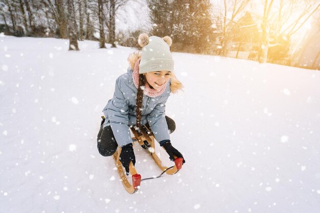 Due bambini cavalcano su una slitta retrò in legno nella soleggiata giornata invernale inverno attivo giochi all'aperto inverno