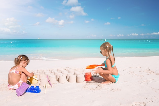 Due bambini che fanno il castello di sabbia e divertirsi in spiaggia tropicale