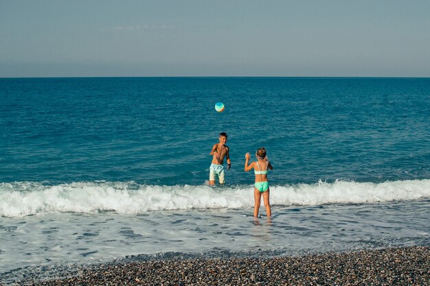 due bambini che giocano a palla sulla spiaggia