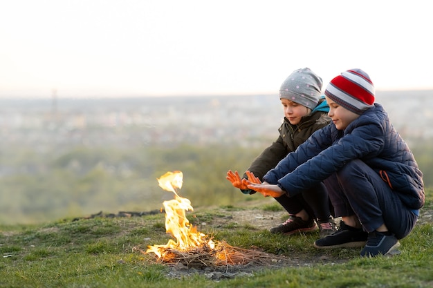 Due bambini che giocano con il fuoco all'aperto quando fa freddo.