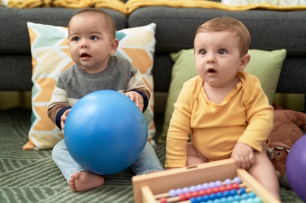 Due bambini che giocano con le palle e l'abaco seduti sul pavimento a casa