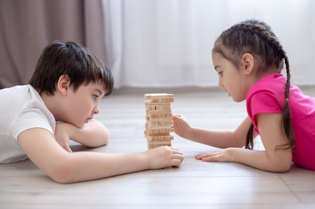 Due bambini che giocano una partita a Jenga sul pavimento