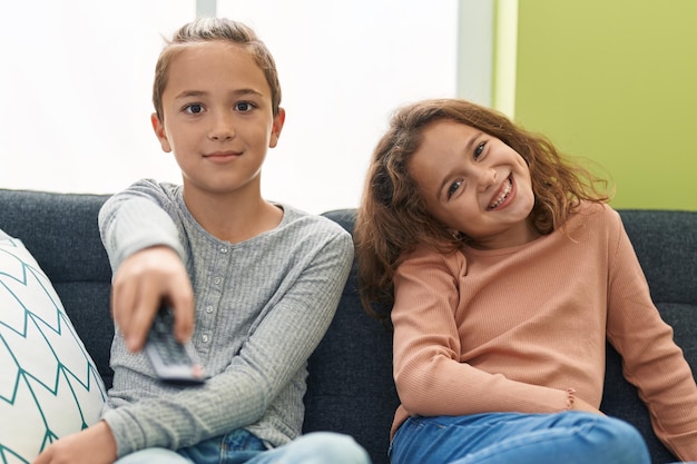 Due bambini che guardano la tv seduti sul divano di casa