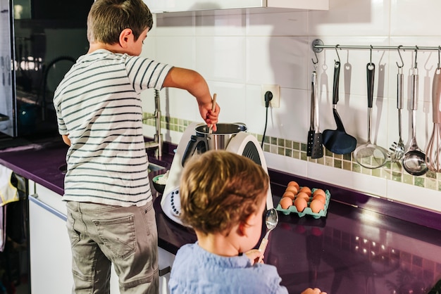 Due bambini che preparano frittelle con un robot da cucina.